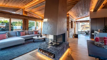 Geräumiges Wohnzimmer mit modernem Kamin, Holzbalkendecke und gemütlicher Sitzecke.