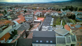 Luftaufnahme einer charmanten Stadt mit vielen Dächern und einer malerischen Landschaft im Hintergrund.