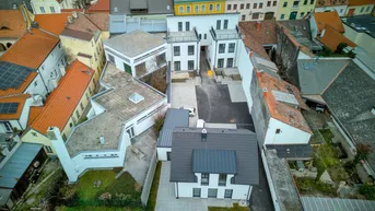 Vogelperspektive auf eine Gruppe von Gebäuden mit modernen und traditionellen Dächern und Höfen.