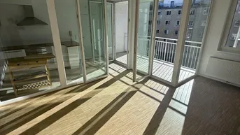 Helles Wohnzimmer mit Parkettboden, großen Glasfronten und Zugang zu einem sonnigen Balkon.