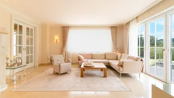 Helles Wohnzimmer mit beigem Sofa, eleganten Möbeln und Zugang zu einem Balkon.
