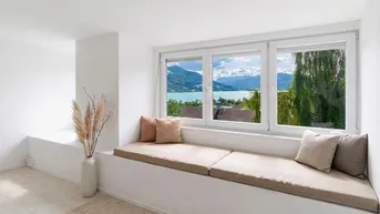Heller Wohnbereich mit integrierter Sitzbank am Fenster und atemberaubendem Blick auf den See und die Berge.