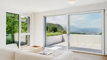 Helles Wohnzimmer mit großen Schiebetüren, die auf eine Terrasse mit Stadt- und Bergblick führen.