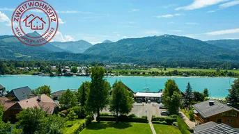 Panoramablick auf den See und die umliegenden Berge von der Immobilie aus unter blauem Himmel.