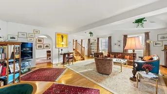 Geräumiges Wohnzimmer mit Parkettboden, gemütlichen Sitzgelegenheiten und einer eleganten Holztreppe.