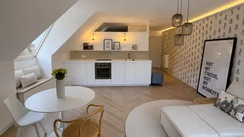Helles, offenes Dachgeschoss-Apartment mit integrierter Küche, Essbereich und gemütlicher Sitzecke unter der Dachschräge.