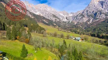Panoramablick auf die majestätischen Berge und grüne Täler mit einem traditionellen Haus in der Ferne.