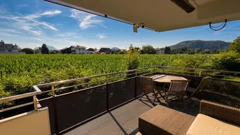 Geräumiger Balkon mit Sitzgelegenheiten und weitem Blick über grüne Felder und die Landschaft.