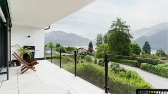 Geräumiger Balkon mit Glasgeländer, Grill und atemberaubendem Blick auf den See und die Berge.