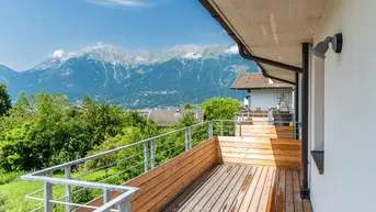 Geräumiger Holzbalkon mit Metallgeländer und atemberaubendem Blick auf die umliegende Berglandschaft.