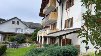Traditionelles Gebäude mit mehreren Balkonen und einem gepflegten Gartenbereich mit Sitzgelegenheiten.