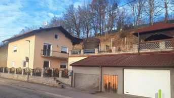 Ansicht des Hauses und der Garage von der Straße mit einem Trampolin im oberen Gartenbereich.