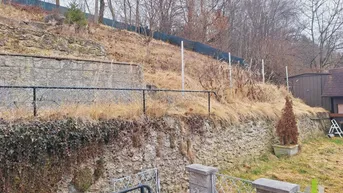 Naturbelassener Hang hinter dem Grundstück mit Trockenmauern und spärlicher Vegetation.