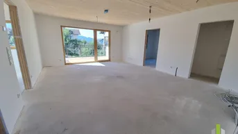 Großer, unfertiger Wohnbereich mit Holzbalkendecke und weitem Blick durch die Terrassentür.