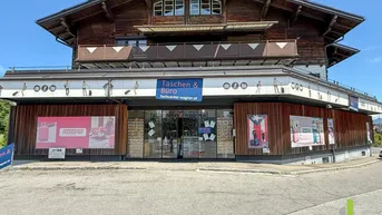 Geschäftsgebäude mit traditioneller Holzfassade im Obergeschoss und moderner Ladenfront im Erdgeschoss.