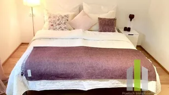 Gemütliches Schlafzimmer mit Doppelbett, Nachttisch und Stehlampe, in hellen Farbtönen gehalten.