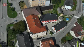 Luftaufnahme eines Wohngebiets mit mehreren Gebäuden, Straßen und Grünflächen.