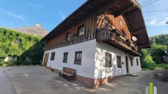 Traditionelles Haus mit Holzbalkon und weißer Fassade unter blauem Himmel.