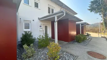 Moderne Hausfassade mit Eingangsbereich, kleinen Sträuchern und Kiesbeet.