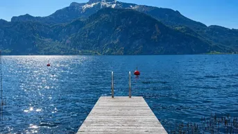 Holzsteg führt in den See mit majestätischem Bergblick unter strahlend blauem Himmel.