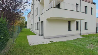 Außenansicht des Gebäudes mit kleiner Terrasse und Rasenfläche im Gartenbereich.