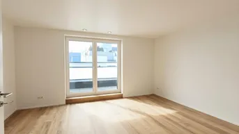 Helles, leeres Zimmer mit Holzboden und Zugang zu einem Balkon oder einer Terrasse.