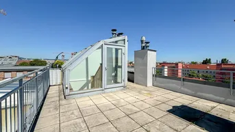 Große Dachterrasse mit Fliesenboden und Zugang zu einem gläsernen Aufbau unter blauem Himmel.