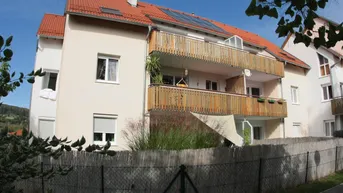 Mehrfamilienhaus mit roten Ziegeldächern, Holzbalustraden und Solaranlage auf dem Dach.