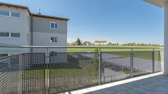 Balkon mit Metallgeländer und weitem Blick über grüne Felder und die ländliche Umgebung.