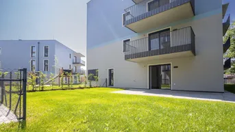 Moderne Wohnanlage mit großzügiger Rasenfläche und privater Terrasse im Erdgeschoss.