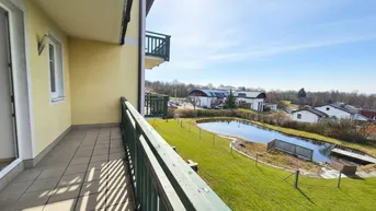 Heller Balkon mit Fliesenboden und weitem Blick auf einen Teich und die umliegende Landschaft.