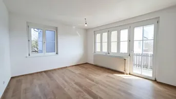 Helles, leeres Zimmer mit Laminatboden und Zugang zu einem Balkon, ideal als Wohnzimmer.