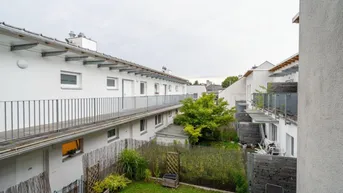 Blick auf den begrünten Innenhof mit kleinen Gärten und Balkonen der Wohneinheiten.