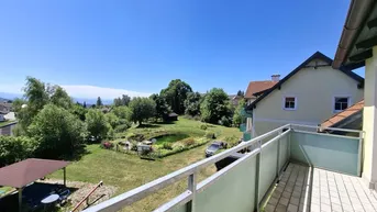 Geräumiger Balkon mit Fliesenboden und Blick auf den Garten mit Teich und die umliegende Landschaft.