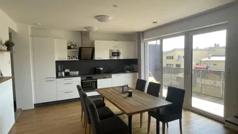 Moderne offene Küche mit Essbereich, Holzboden und Zugang zu einem Balkon.