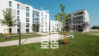 Moderne Wohnanlage mit mehreren Gebäuden, Grünflächen und klarem Himmel an einem sonnigen Tag.