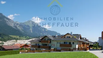 Modernes Wohngebäude in alpiner Umgebung mit beeindruckendem Bergblick unter blauem Himmel.