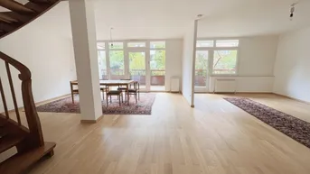 Helles, offenes Wohn-Esszimmer mit Parkettboden, Holztreppe und Zugang zum Balkon.