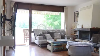 Gemütliches Wohnzimmer mit Kamin, Holzboden und Zugang zu einer Außenterrasse.