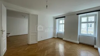 Helles Zimmer mit Fischgrätparkettboden, weißen Wänden und zwei Fenstern, das viel Tageslicht bietet.