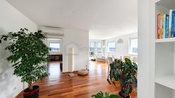 Helles, offenes Wohn- und Esszimmer mit Holzboden, großen Fenstern und Stadtblick.