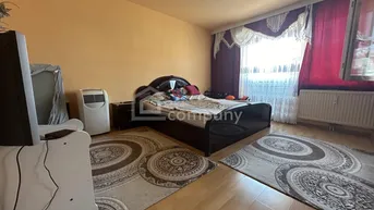 Schlafzimmer mit Doppelbett, Parkettboden und Fenster mit Vorhängen.