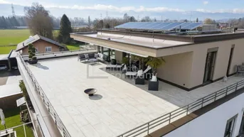 Großzügige Dachterrasse mit modernen Loungemöbeln, Feuerstelle und Panoramablick auf die Berge.