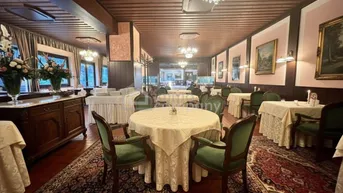 Traditioneller Speisesaal mit elegant gedeckten Tischen, Teppichboden und Kronleuchtern, ideal für Veranstaltungen.