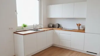 Moderne Küche mit weißen Schränken, Holz-Arbeitsplatte und großem Fenster für viel Tageslicht.