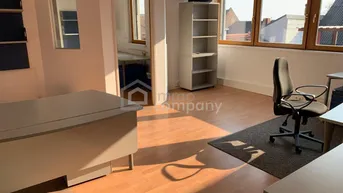 Helles Büro mit Holzfußboden, großen Fenstern und funktionalen Büromöbeln, ideal für produktives Arbeiten.