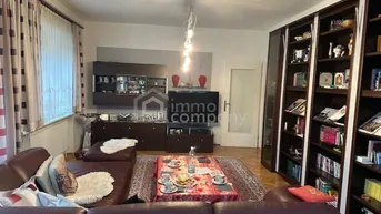 Geräumiges Wohnzimmer mit braunem Ledersofa, Couchtisch und großer Bücherwand.