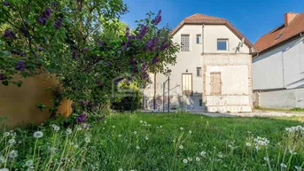 Rückansicht des Hauses mit großem Garten und blühendem Fliederbusch.