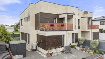 Moderne Doppelhaushälfte mit heller Fassade, dunklen Holzdetails und dekorativen Balkongeländern.