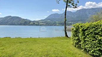 Weitläufiger Blick auf den See und die majestätischen Berge, umgeben von einer gepflegten Rasenfläche.